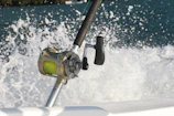 Close-up of a digital fishing reel spinning as a big catch struggles underwater.