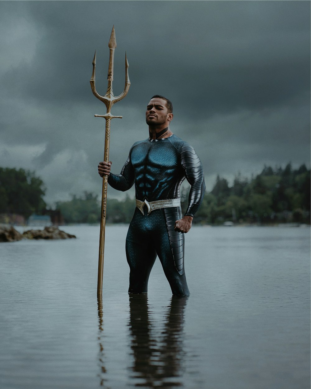 a man standing in the water holding a large metal pole