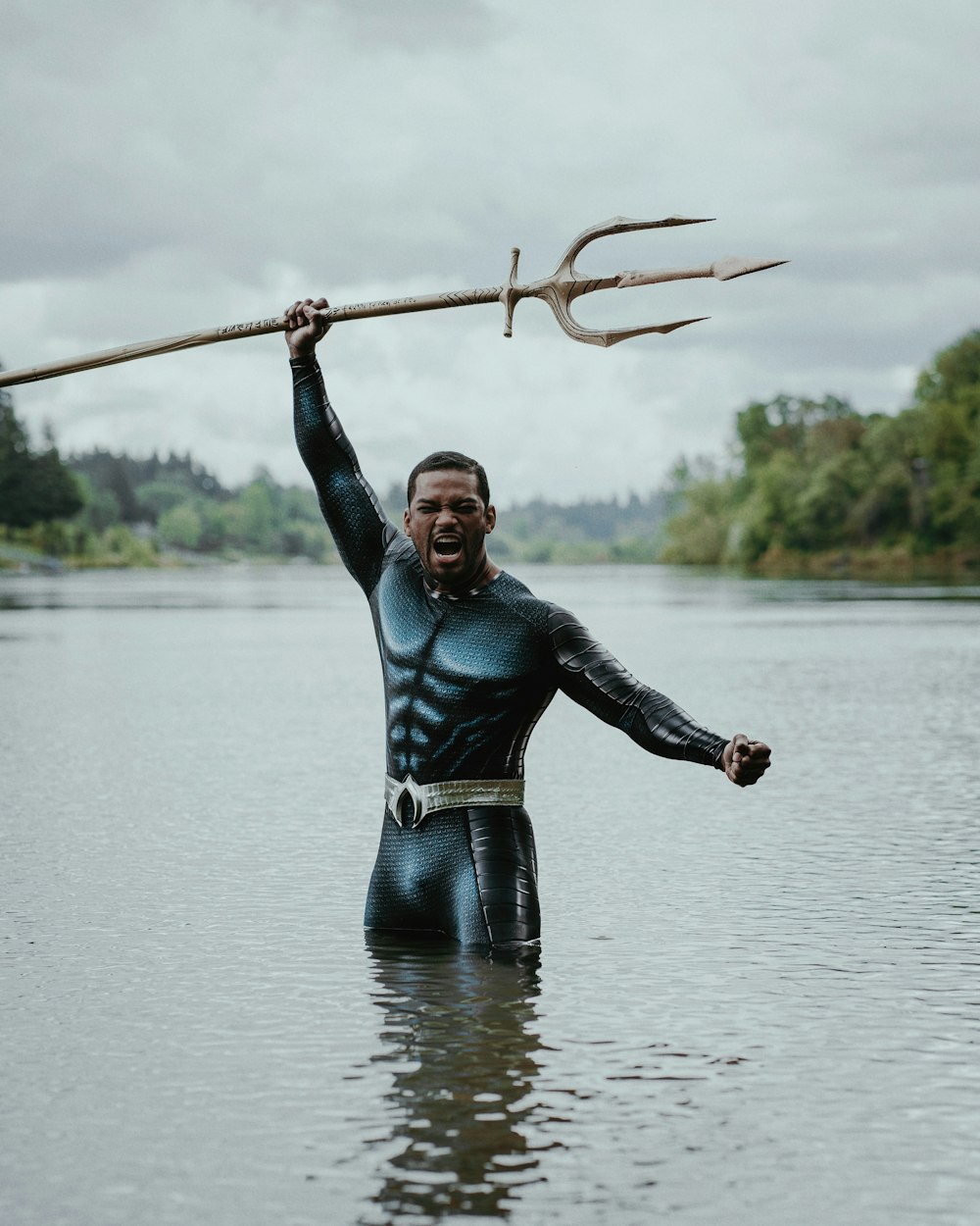Un hombre con un traje de neopreno sostiene un palo en el agua
