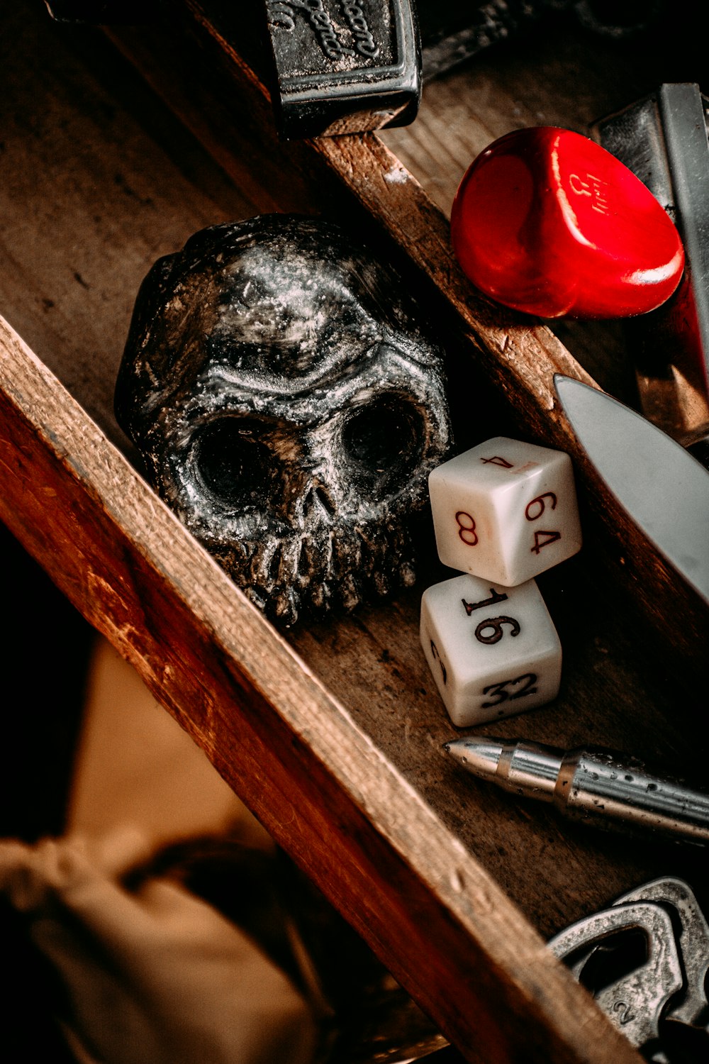 a wooden table topped with dice and a skull