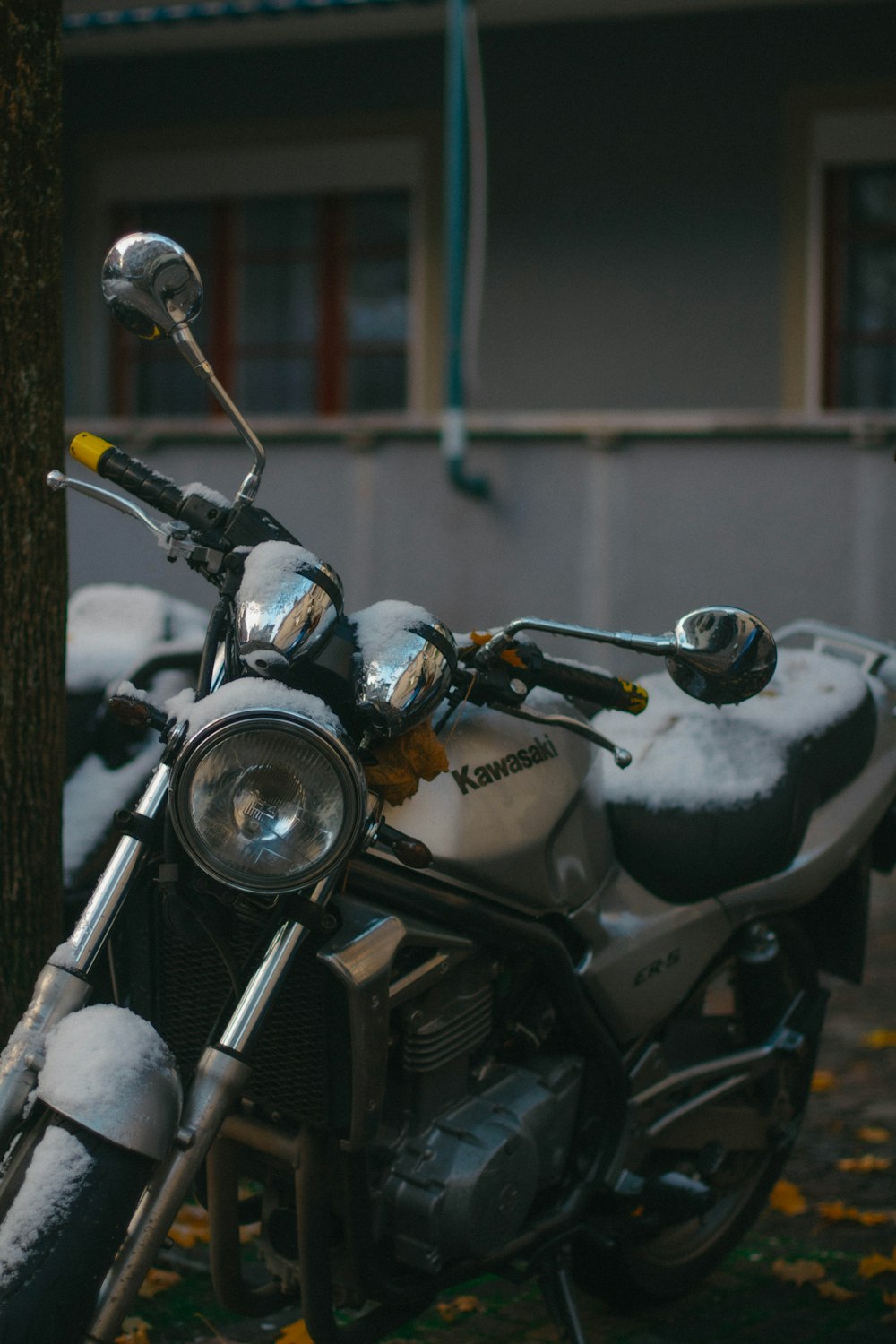 a motorcycle parked next to a tree covered in snow