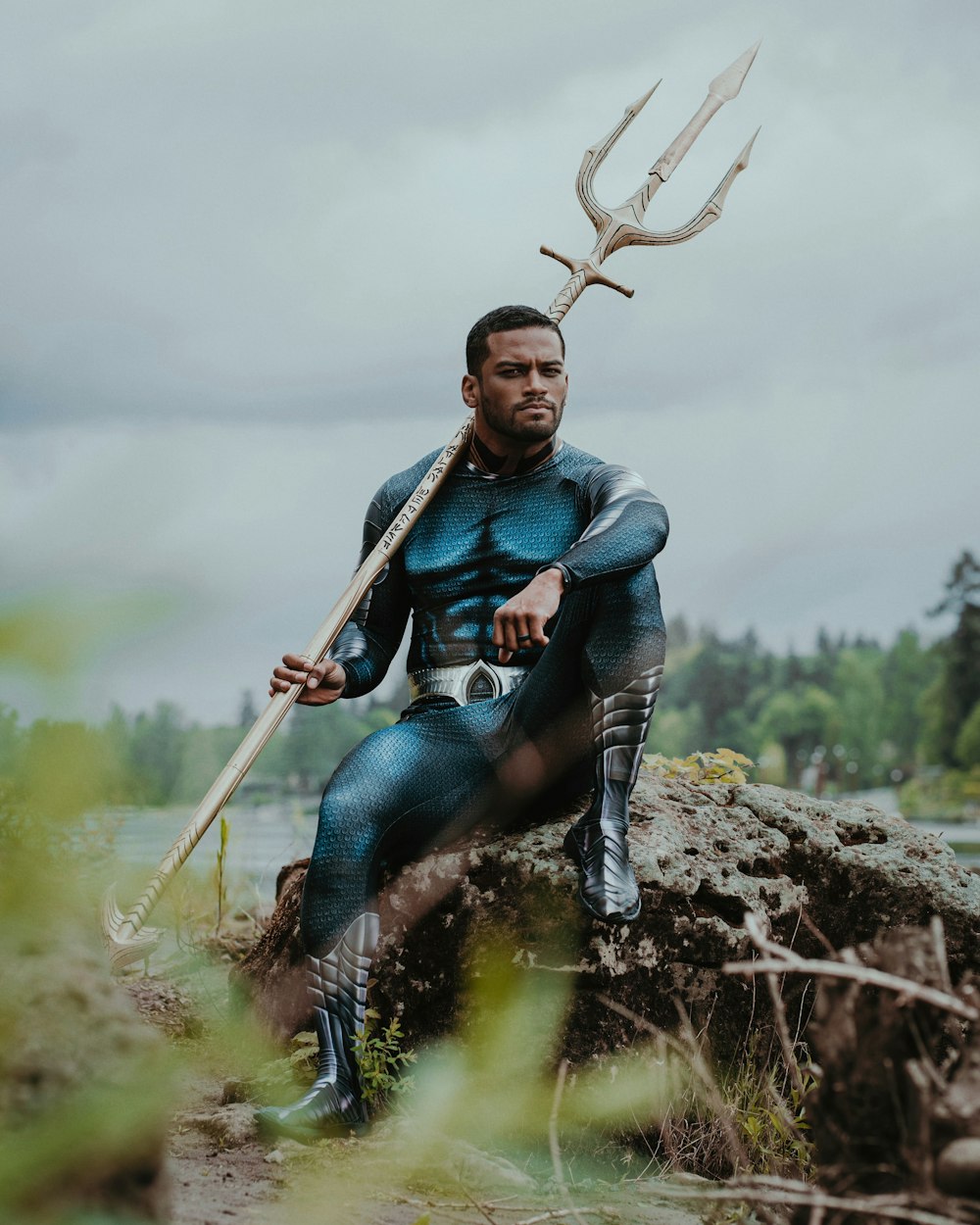 a man in a blue suit sitting on a rock