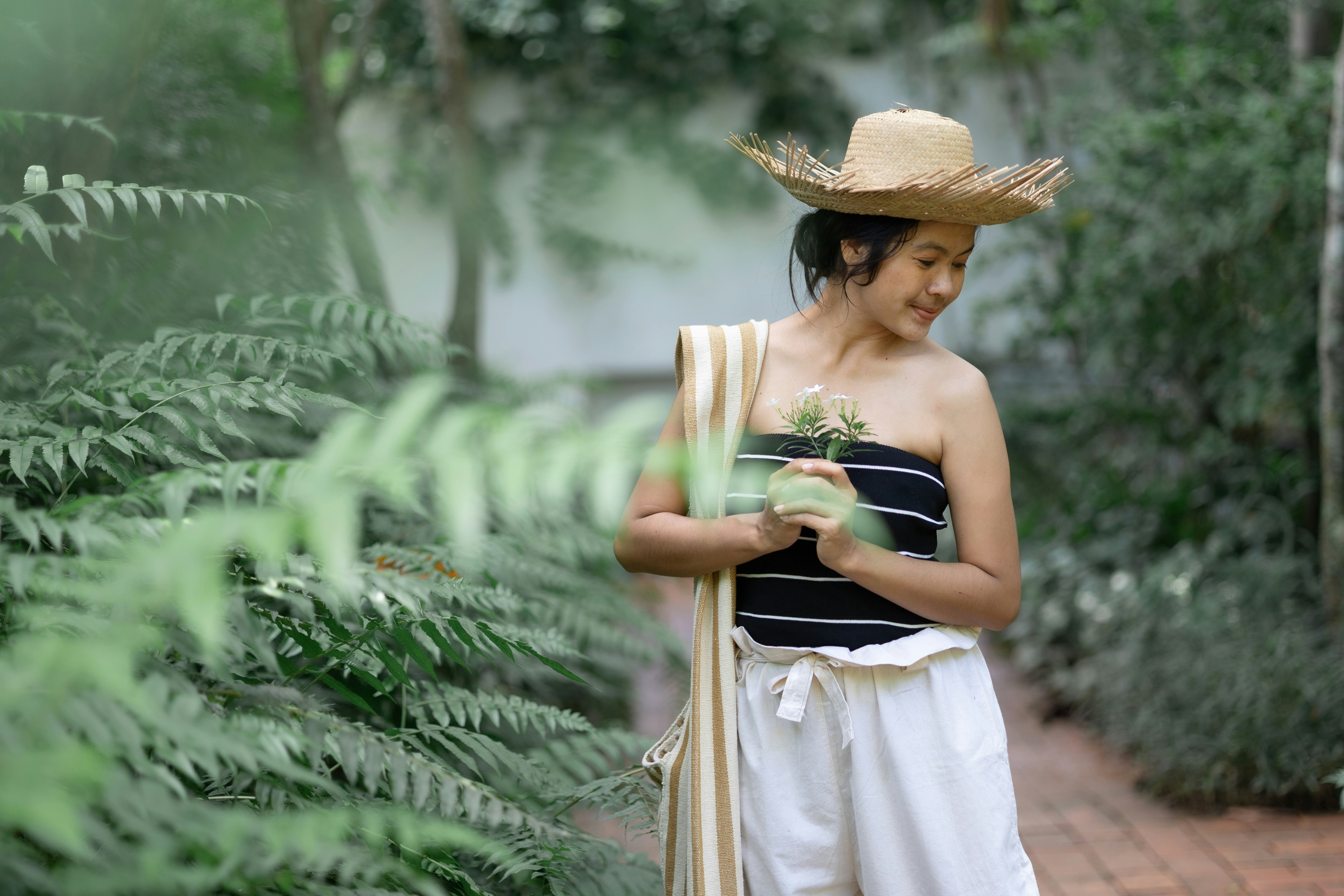 a woman wearing a straw hat and holding a plant