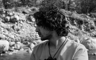 A black and white portrait capturing a thoughtful subject in a natural outdoor setting, reflecting cultural identity.