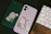 A close-up of a pastel pink Vivacover phone case with a delicate cartoon design held in a hand.