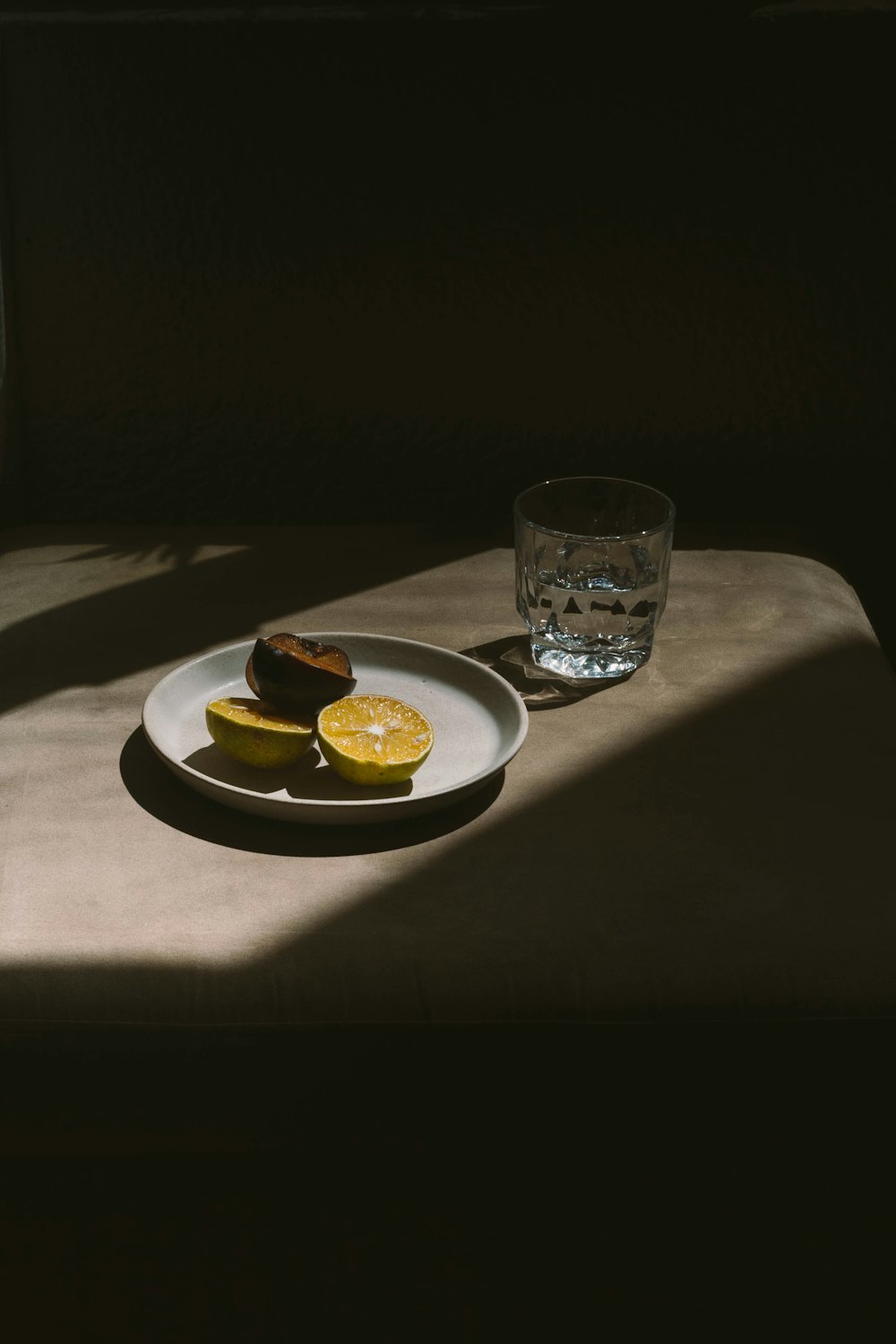 a white plate topped with sliced lemons next to a glass of water