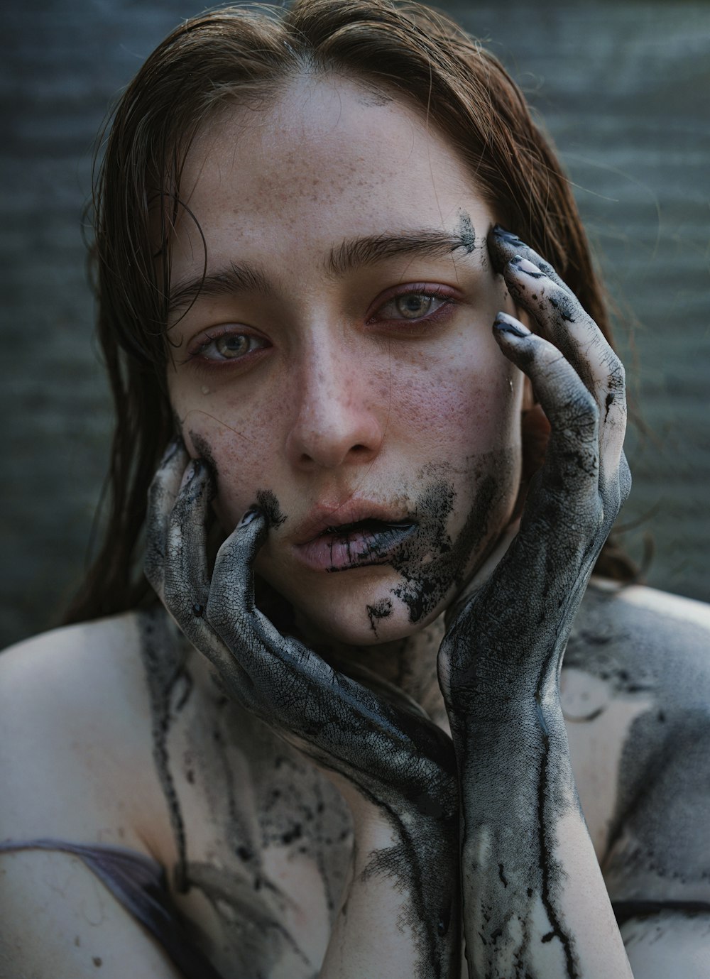 a woman with mud on her face and hands