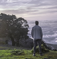 a man standing on top of a lush green hillside