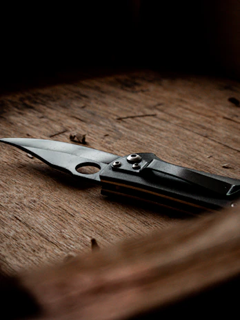 A vintage folding knife resting on a wooden table with warm natural light highlighting its craftsmanship.