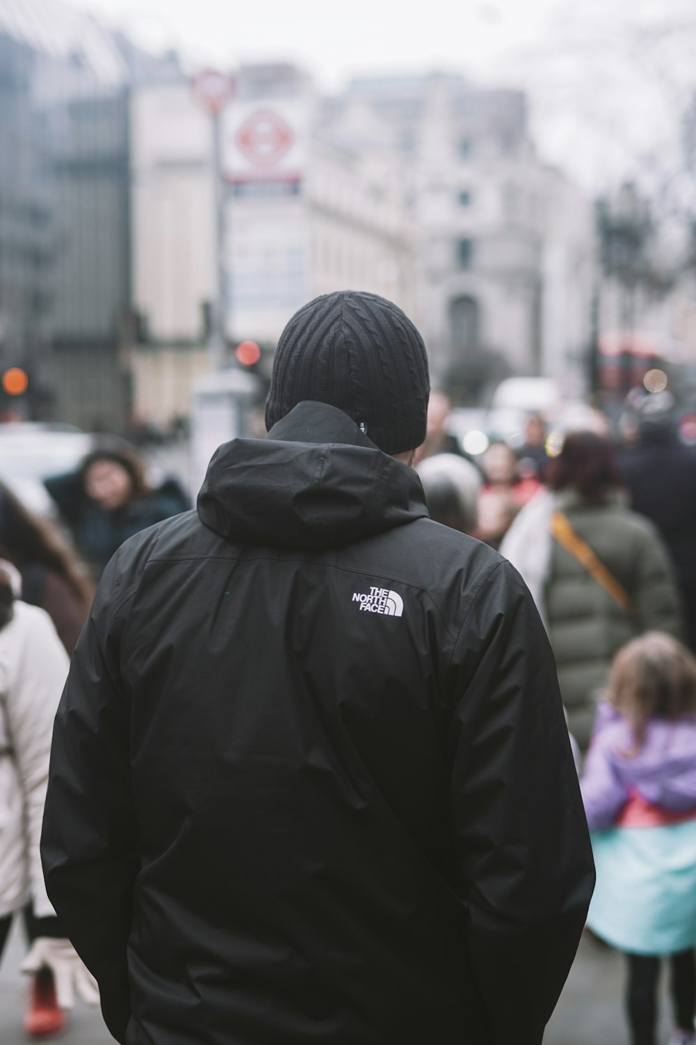 a man in a black jacket is walking down the street