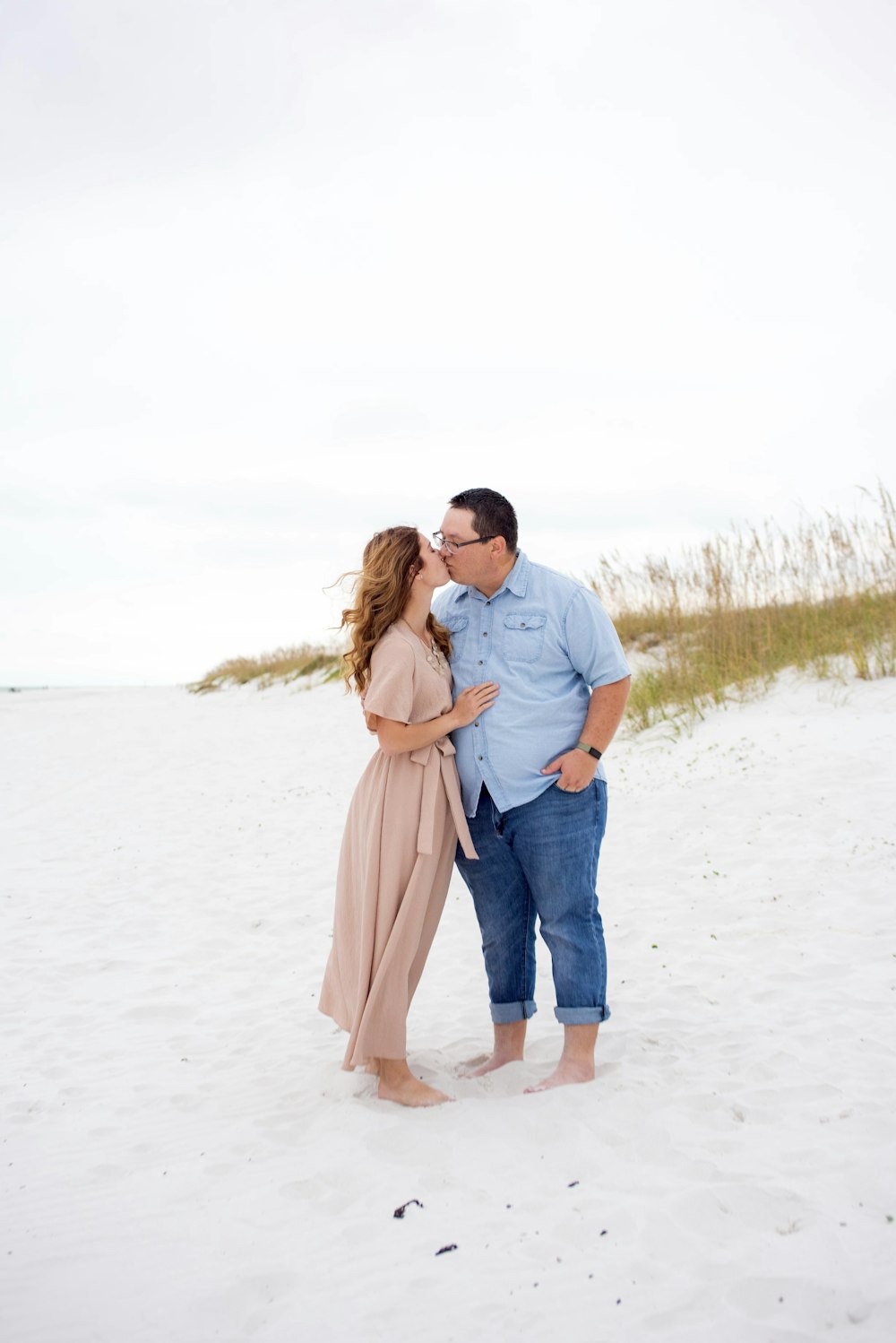 a man and woman kissing on the beach