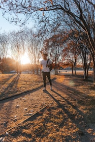 A person jogging in a sunny park, smiling and enjoying the morning.