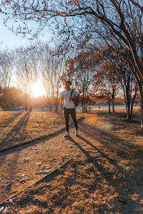 A person jogging in a park during sunrise, surrounded by trees.