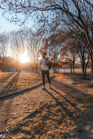 A joyful senior runner jogging in a park during sunrise.