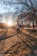 A person jogging in a park surrounded by lush greenery and bright morning sunlight.