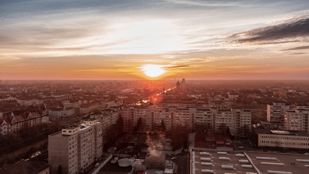 the sun is setting over a city with tall buildings