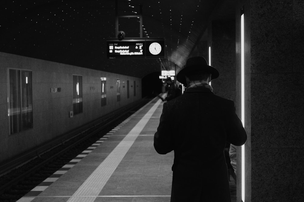 a man standing in a train station next to a train