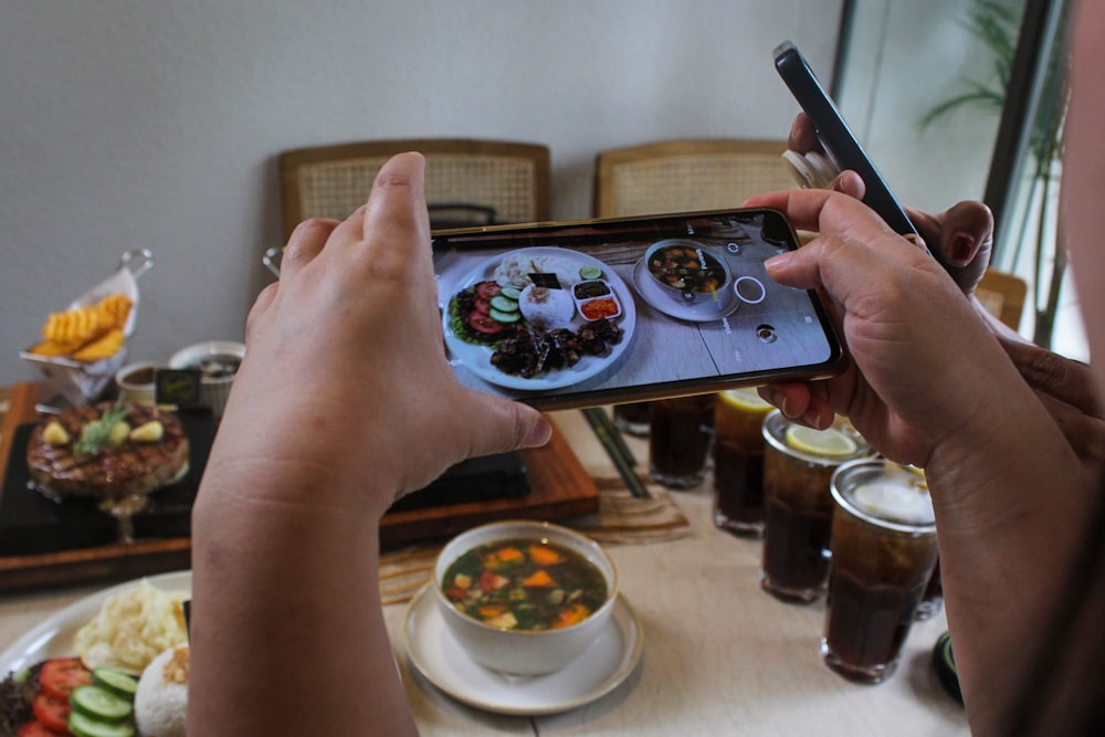 une personne prenant une photo de nourriture sur un téléphone cellulaire