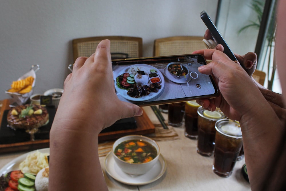 una persona tomando una foto de comida en un teléfono celular