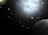 A vast and dark space scene peppered with numerous small celestial objects resembling stars and planets. A large, bright nebula dominates the upper part of the image, casting a diffuse glow against the black backdrop. In the lower right corner, a prominent planet is partially visible, appearing spherical and shaded in gray.