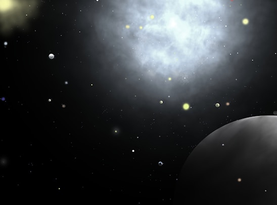 A vast and dark space scene peppered with numerous small celestial objects resembling stars and planets. A large, bright nebula dominates the upper part of the image, casting a diffuse glow against the black backdrop. In the lower right corner, a prominent planet is partially visible, appearing spherical and shaded in gray.