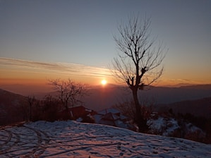 A serene Alaskan landscape at sunset with a memorial candle glowing softly among wildflowers.
