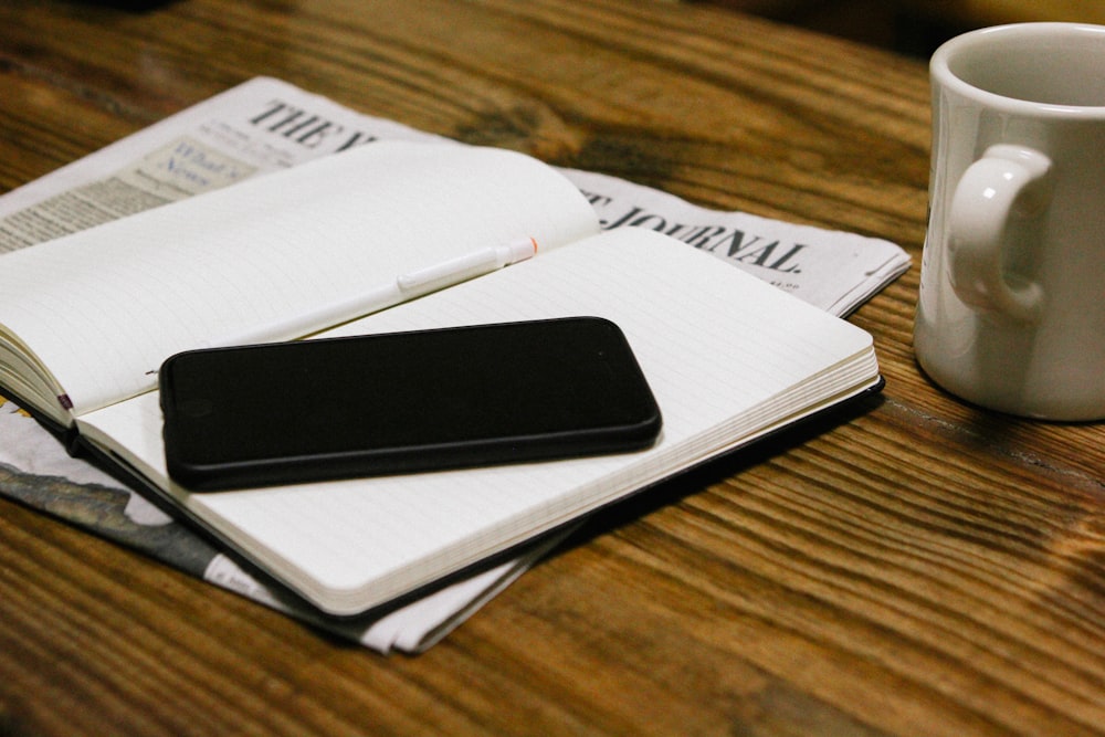 a cup of coffee and a cell phone on a table