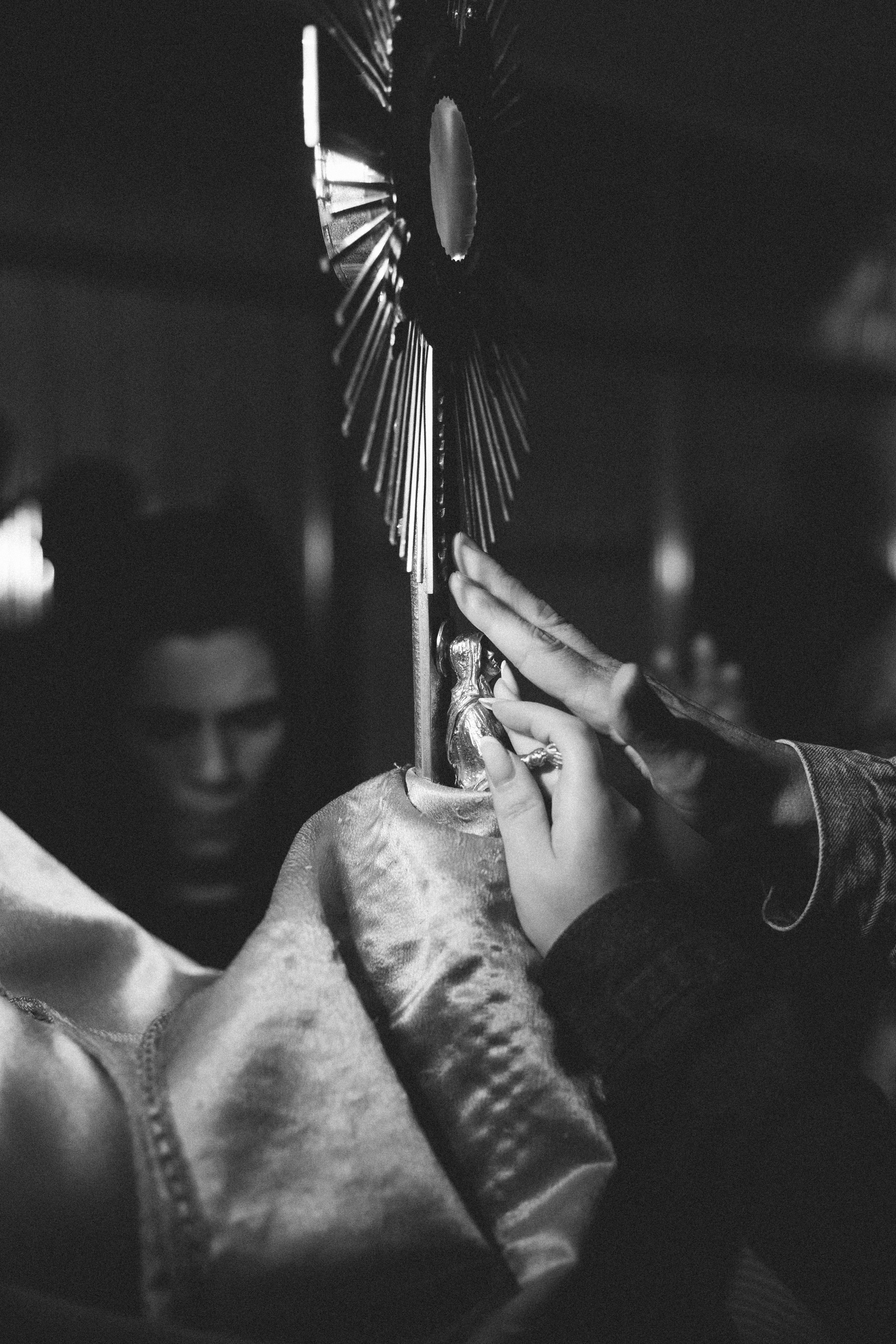 A black and white photo of a person holding a cross