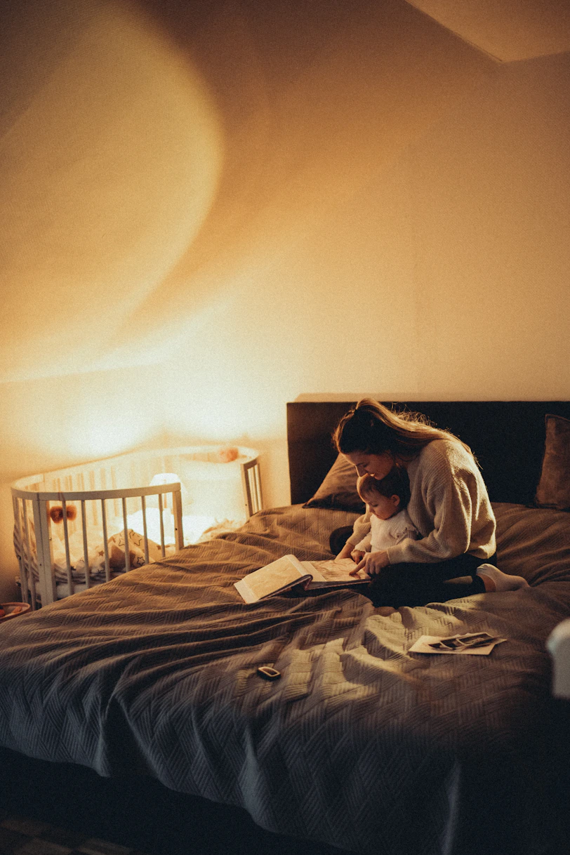 a woman sitting on a bed reading a book