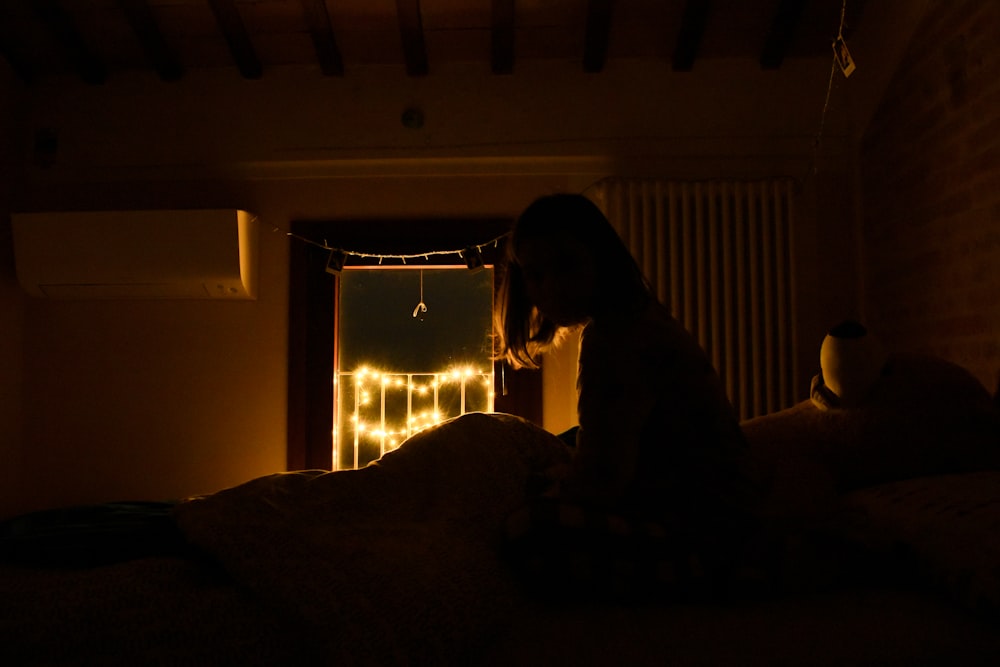 a person sitting on a bed in a dark room