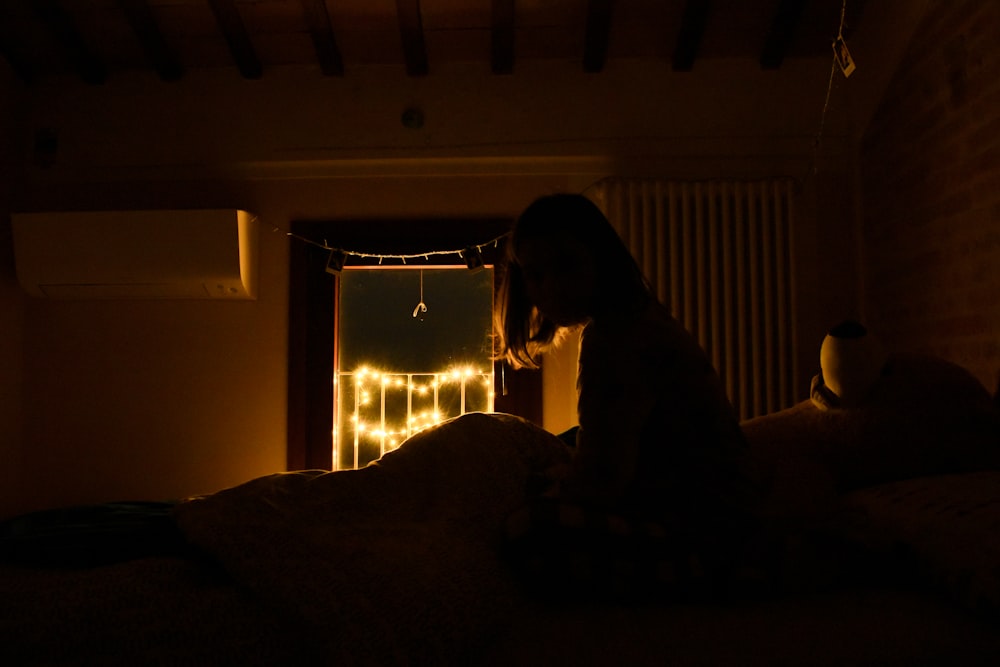 Una persona sentada en una cama en una habitación oscura