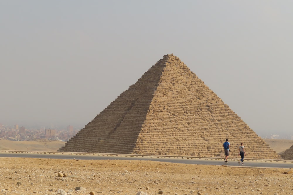 two people walking in front of the pyramids of giza