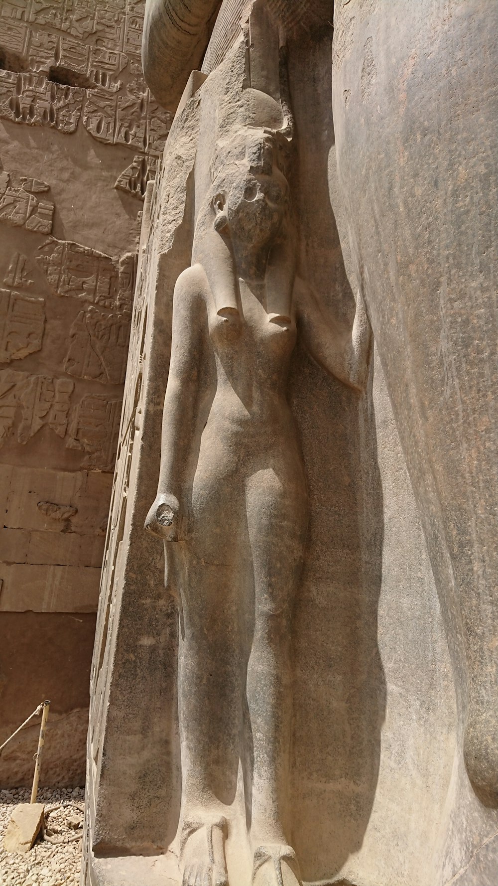 a statue of a woman standing next to a stone wall