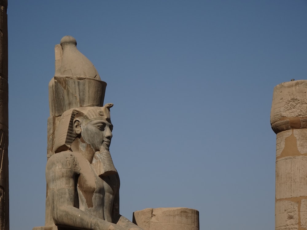 a statue of an egyptian god next to a pillar