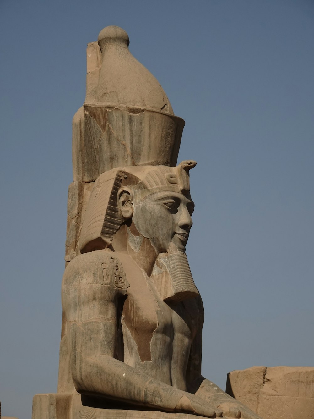 Une grande statue d’un dieu égyptien assis devant un bâtiment