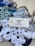 A collection of crocheted snowflakes in various shades of blue and white is spread on a surface. They are accompanied by a rustic twine and a tag labeled 'Jill-Of-All-Trades Crocheted Goods'.