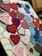 A collection of crocheted hearts and snowflakes pinned onto a fabric-covered board. The hearts are made in various colors like red, pink, and purple, while the snowflakes are mostly in shades of blue and white. They are arranged in an overlapping pattern, displaying a variety of crochet designs.