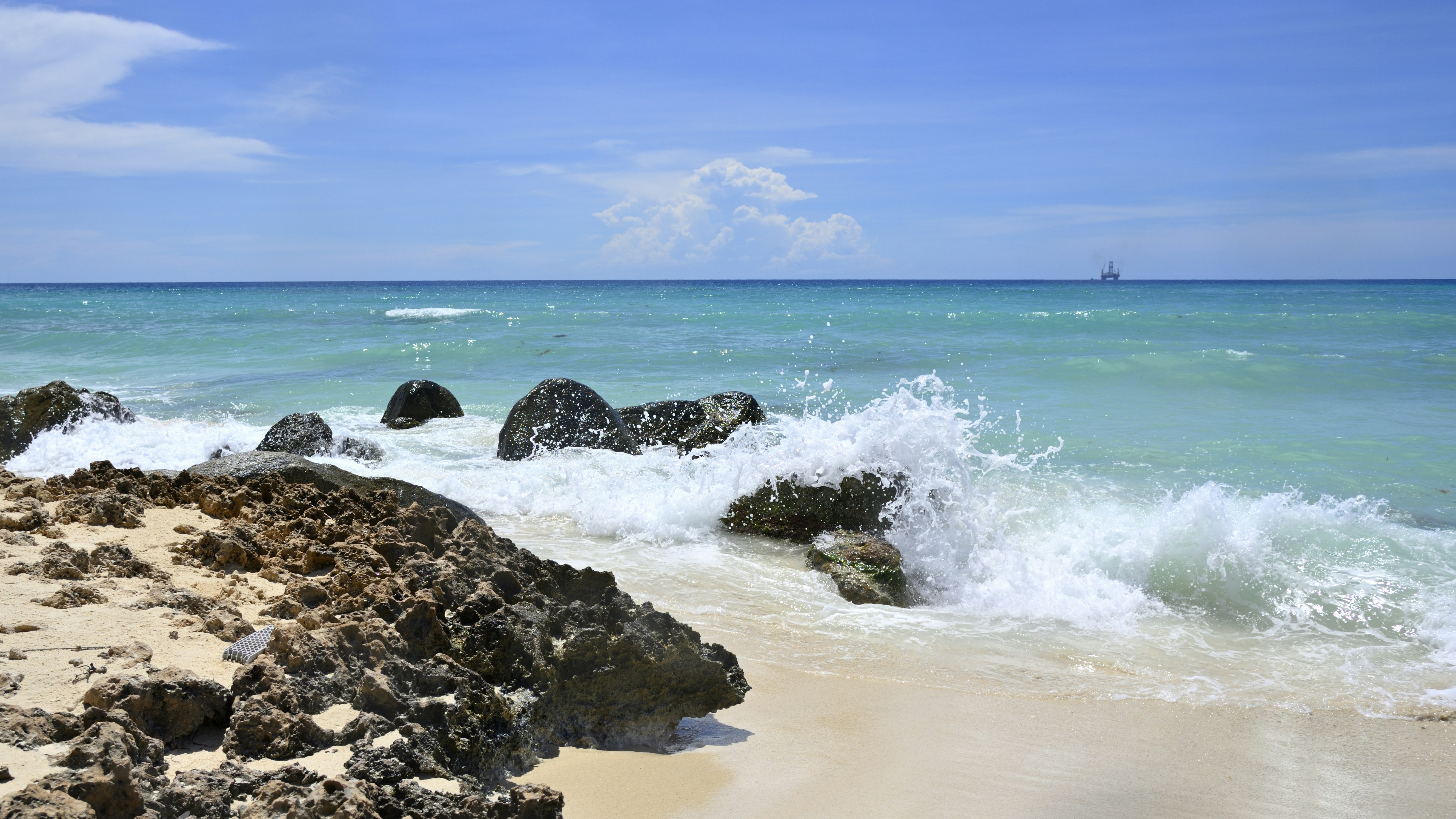 a beach with rocks and water splashing on it