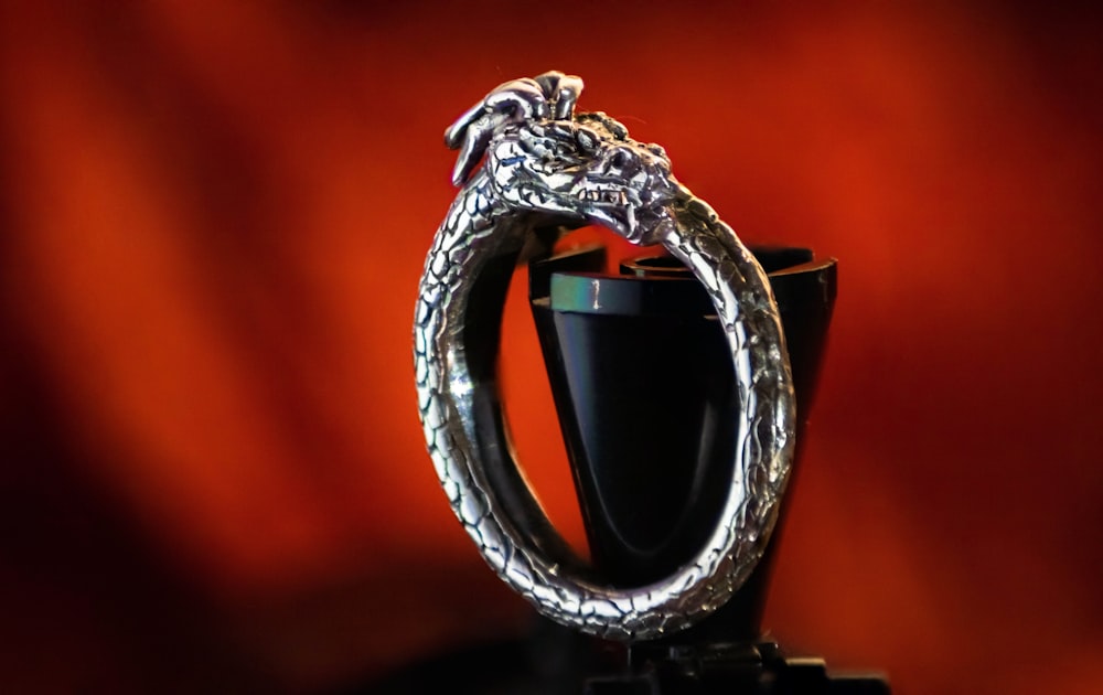 a silver dragon ring sitting on top of a black cup