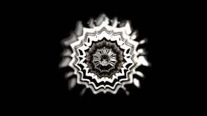 A black background highlights a symmetrical, abstract pattern resembling a radial wave or sound wave emanating from the center. The design features intricate, wavy lines with a metallic sheen, creating a 3D effect.