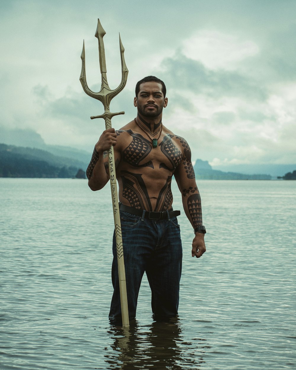 Un hombre parado en el agua sosteniendo una gran lanza