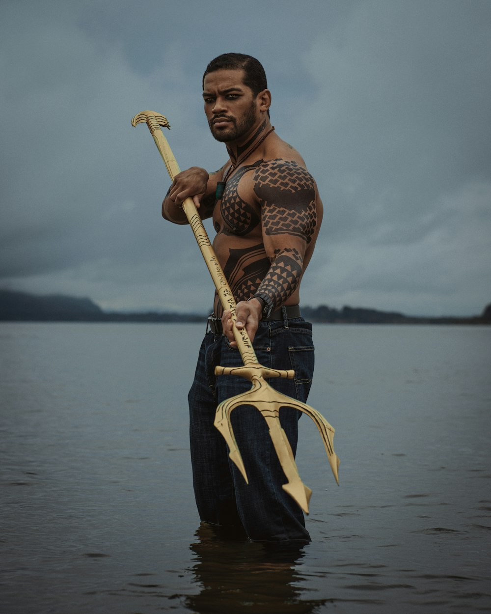 a man standing in the water holding a giant axe
