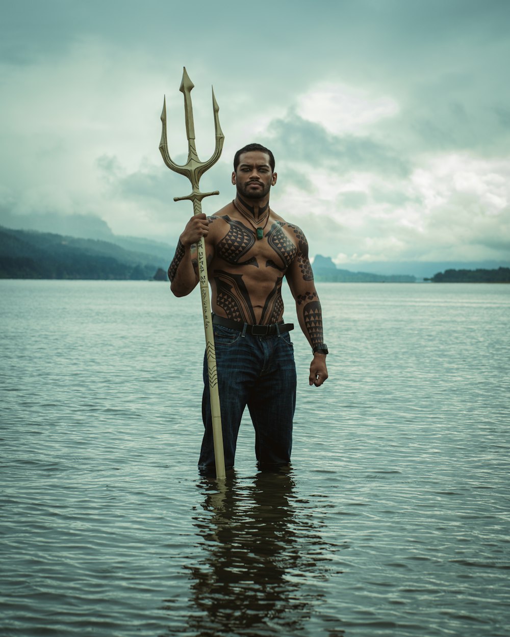 Un hombre parado en un cuerpo de agua sosteniendo un poste