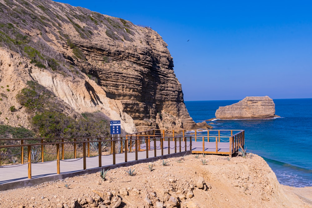 a wooden walkway next to the ocean near a cliff
