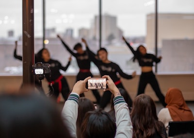 Close-up of a camera filming a dynamic urban dance performance at dusk.