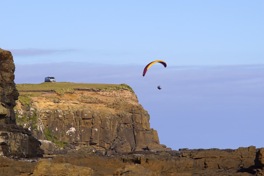 a paraglider is flying over a rocky cliff