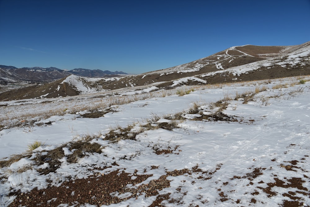 a snow covered field with mountains in the background