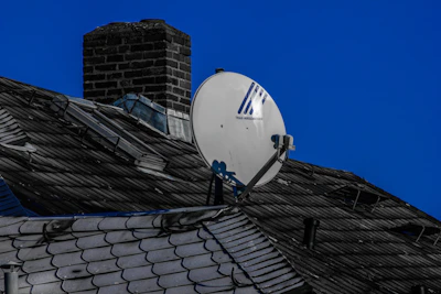 A freshly installed dark blue shingle roof on a suburban home under clear skies.