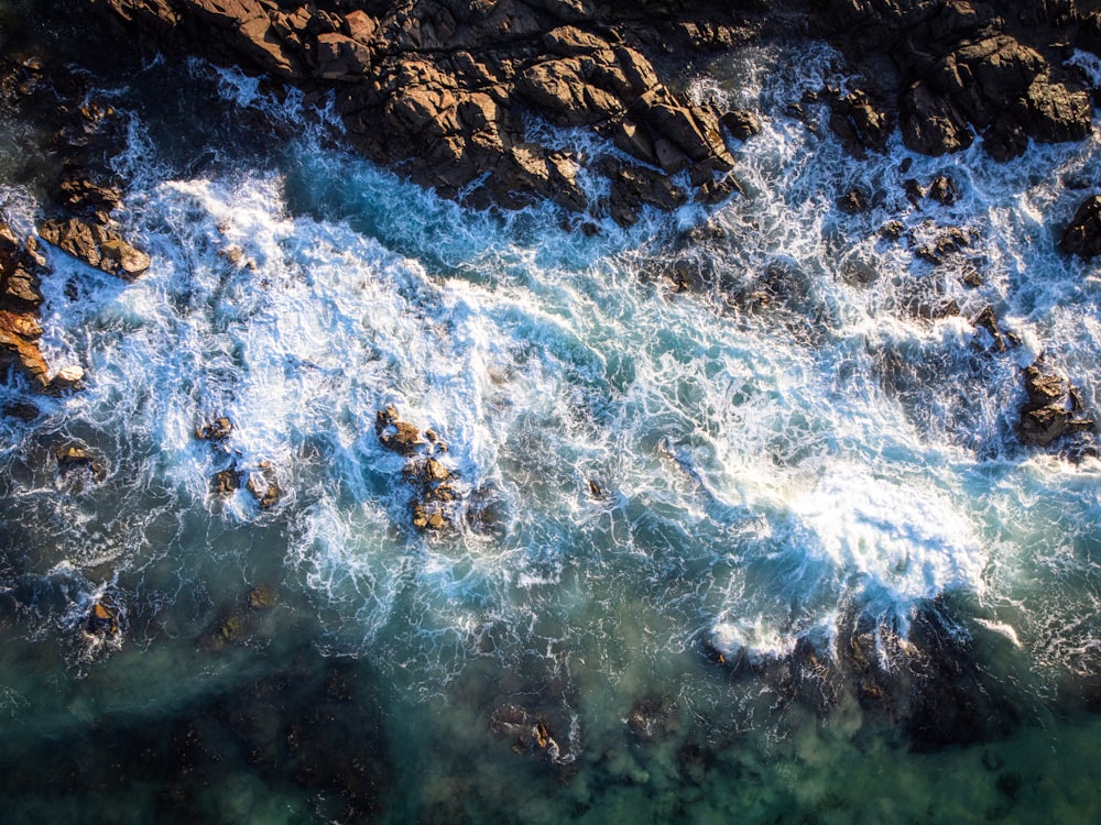 an aerial view of the ocean and rocks