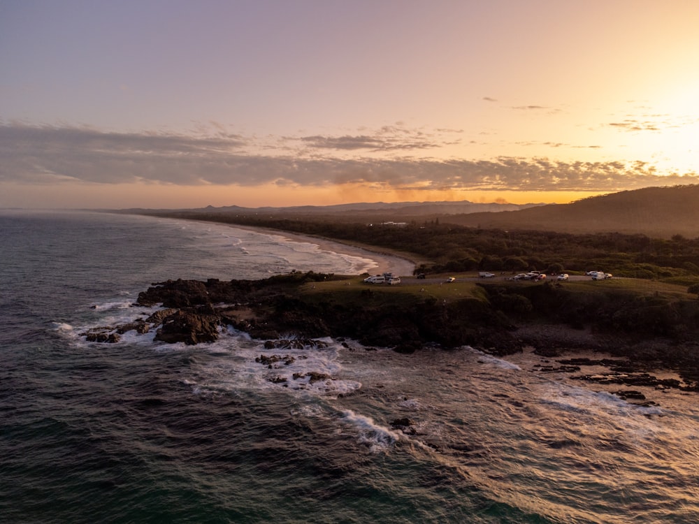 an aerial view of a beach with a sunset in the background